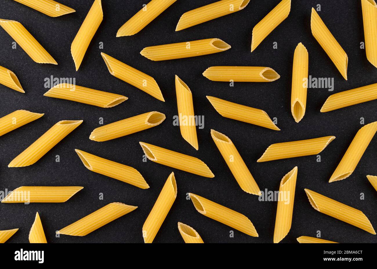 Penne rigate Pasta Muster auf schwarzem Hintergrund, Draufsicht, flache Lay Textur Stockfoto