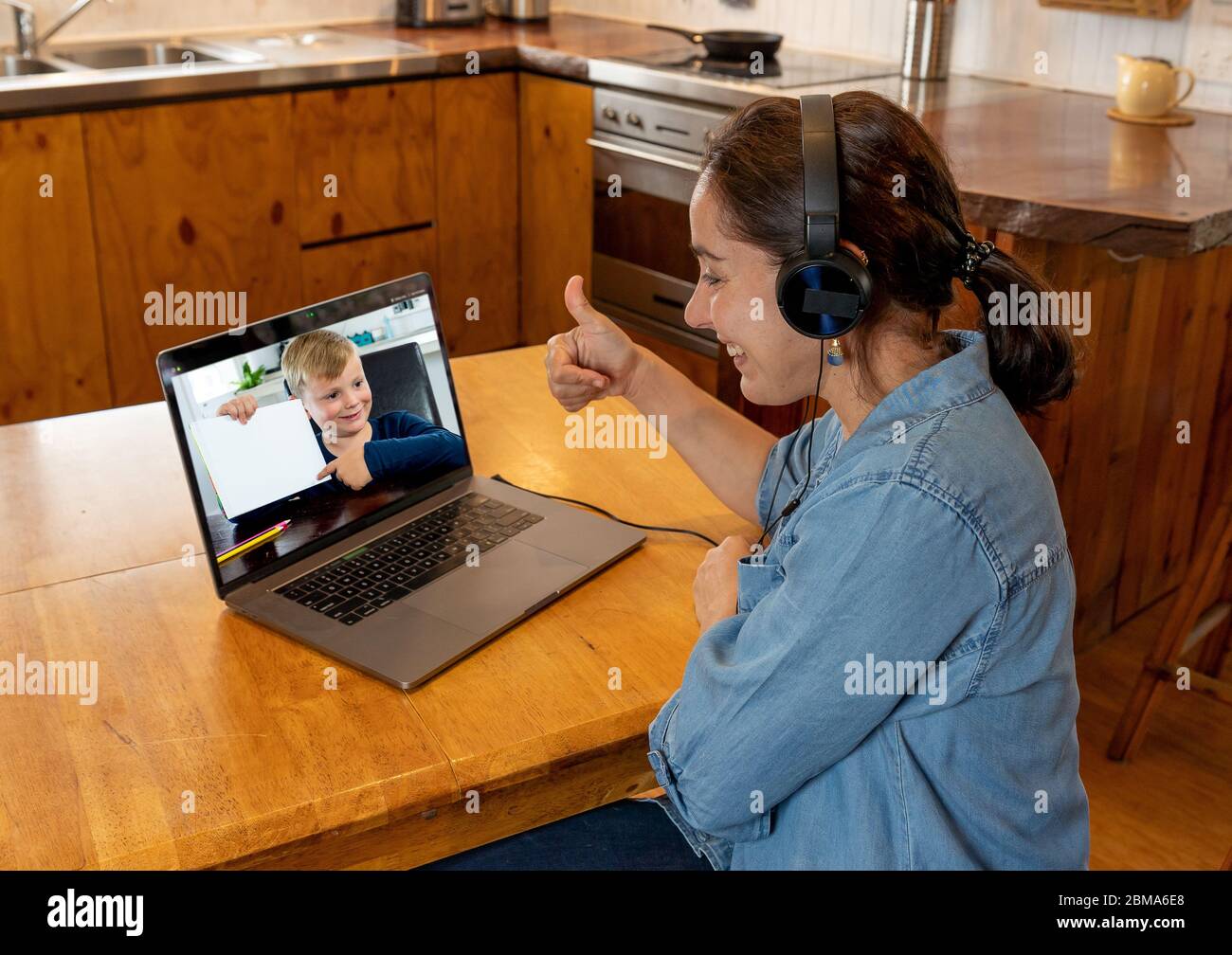 COVID-19 Online-Schulung. Grundlehrer und Schüler interagieren in Live-Video-Lektion. Tutorin mit Headset und Laptop, die von zu Hause aus arbeitet Stockfoto
