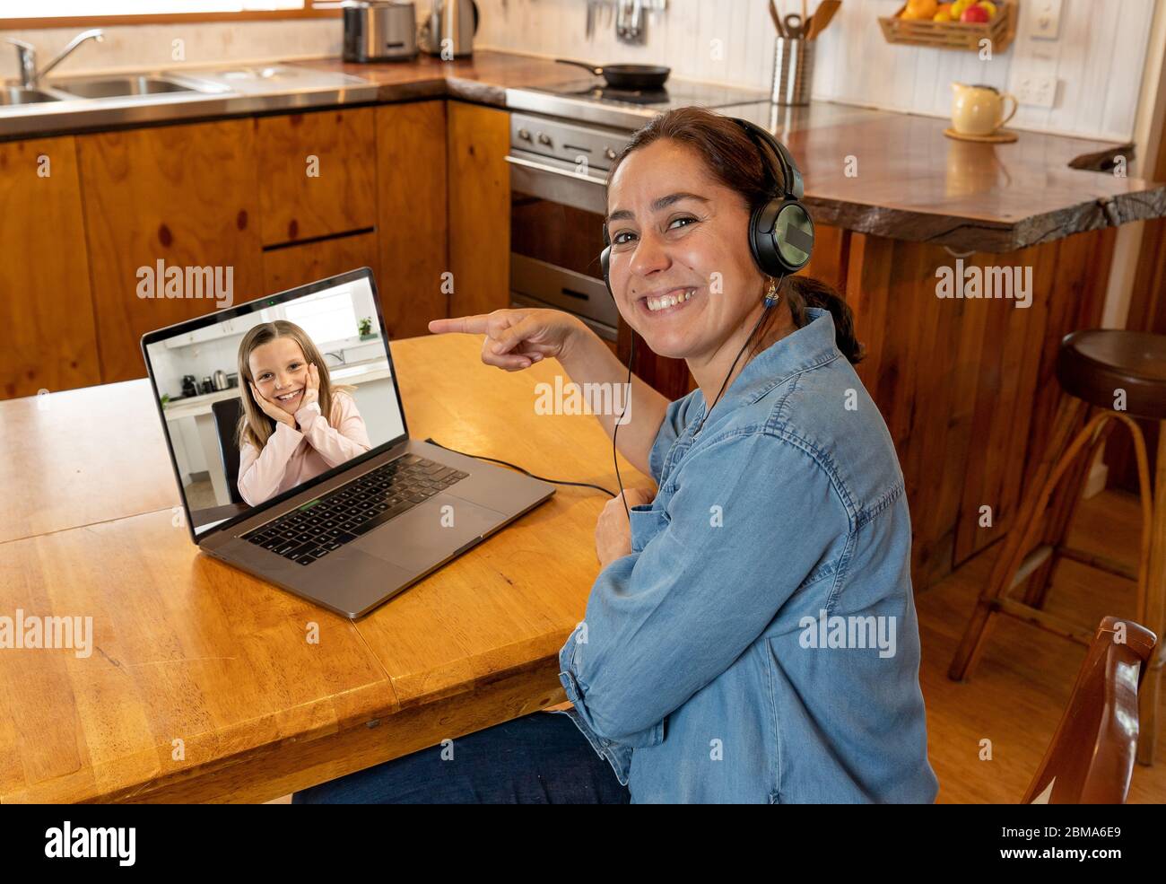 COVID-19 Online-Schulung. Grundlehrer und Schüler interagieren in Live-Video-Lektion. Tutorin mit Headset und Laptop, die von zu Hause aus arbeitet Stockfoto