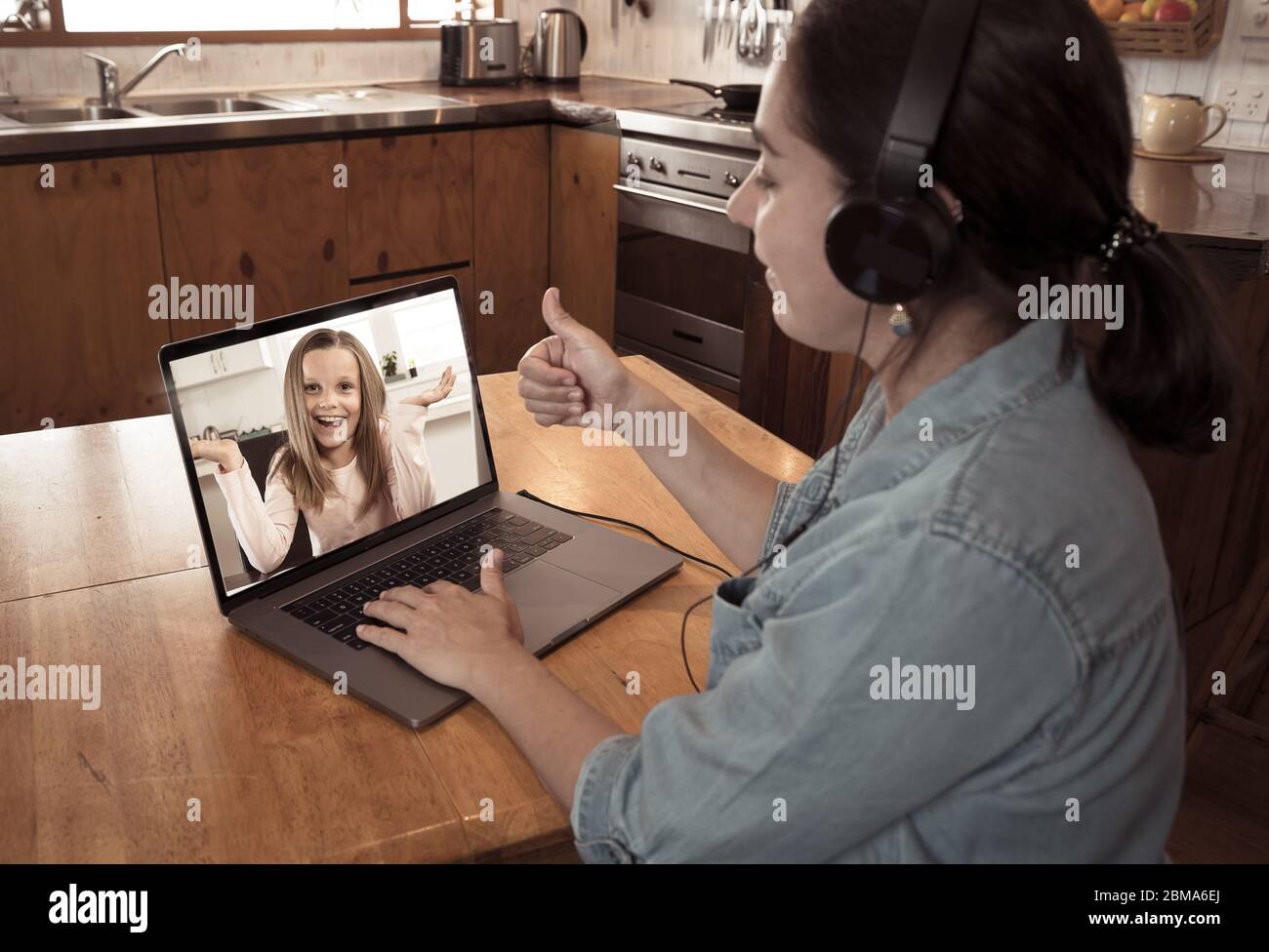 COVID-19 Online-Schulung. Grundlehrer und Schüler interagieren in Live-Video-Lektion. Tutorin mit Headset und Laptop, die von zu Hause aus arbeitet Stockfoto