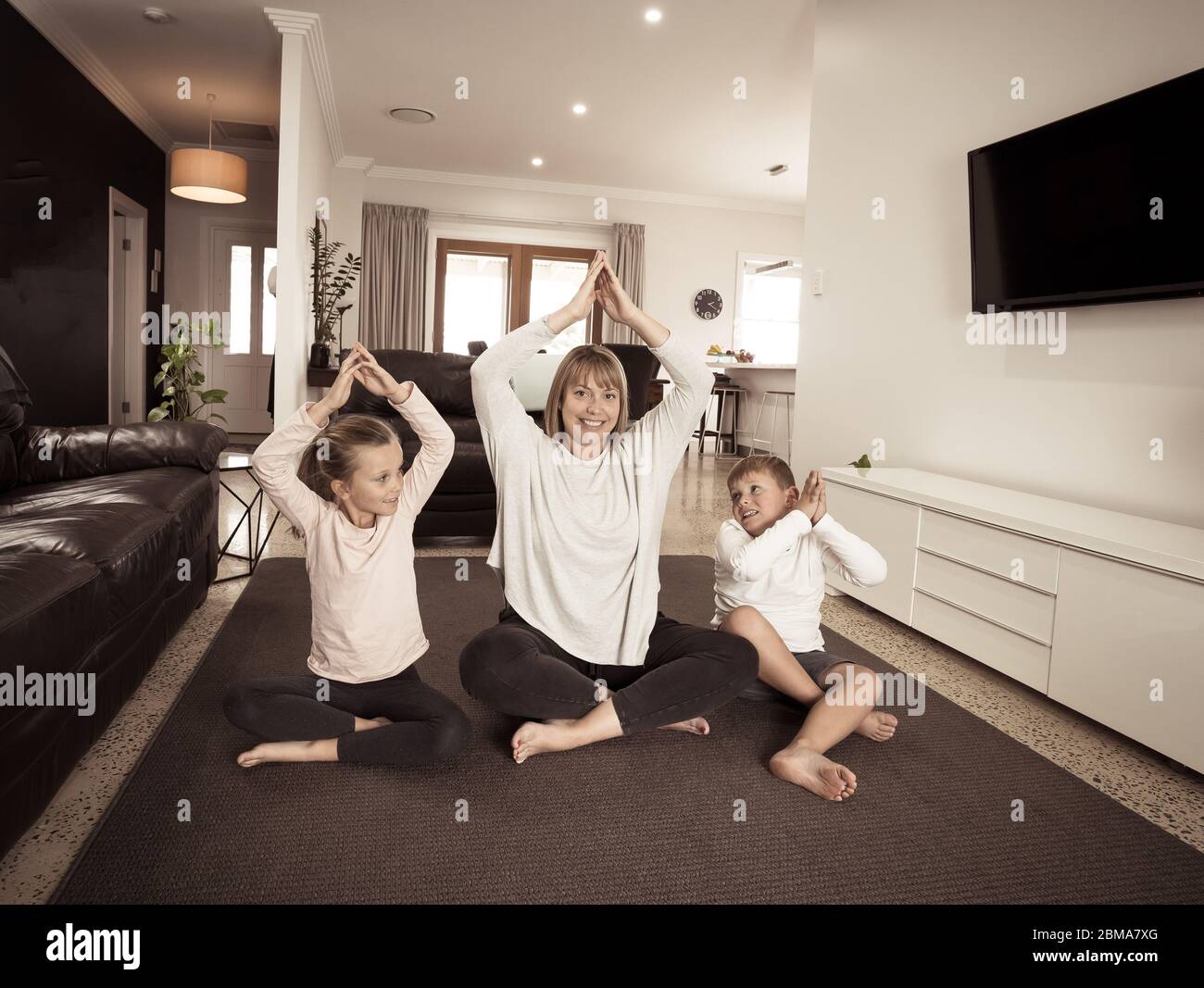 COVID-19-Abschaltung. Kaukasische Familie, die zu Hause Yoga in Quarantäne macht. Mutter, Tochter und Sohn, die während des Lockdowns meditieren. Gesundheit, Trainingsaufenthalt Stockfoto