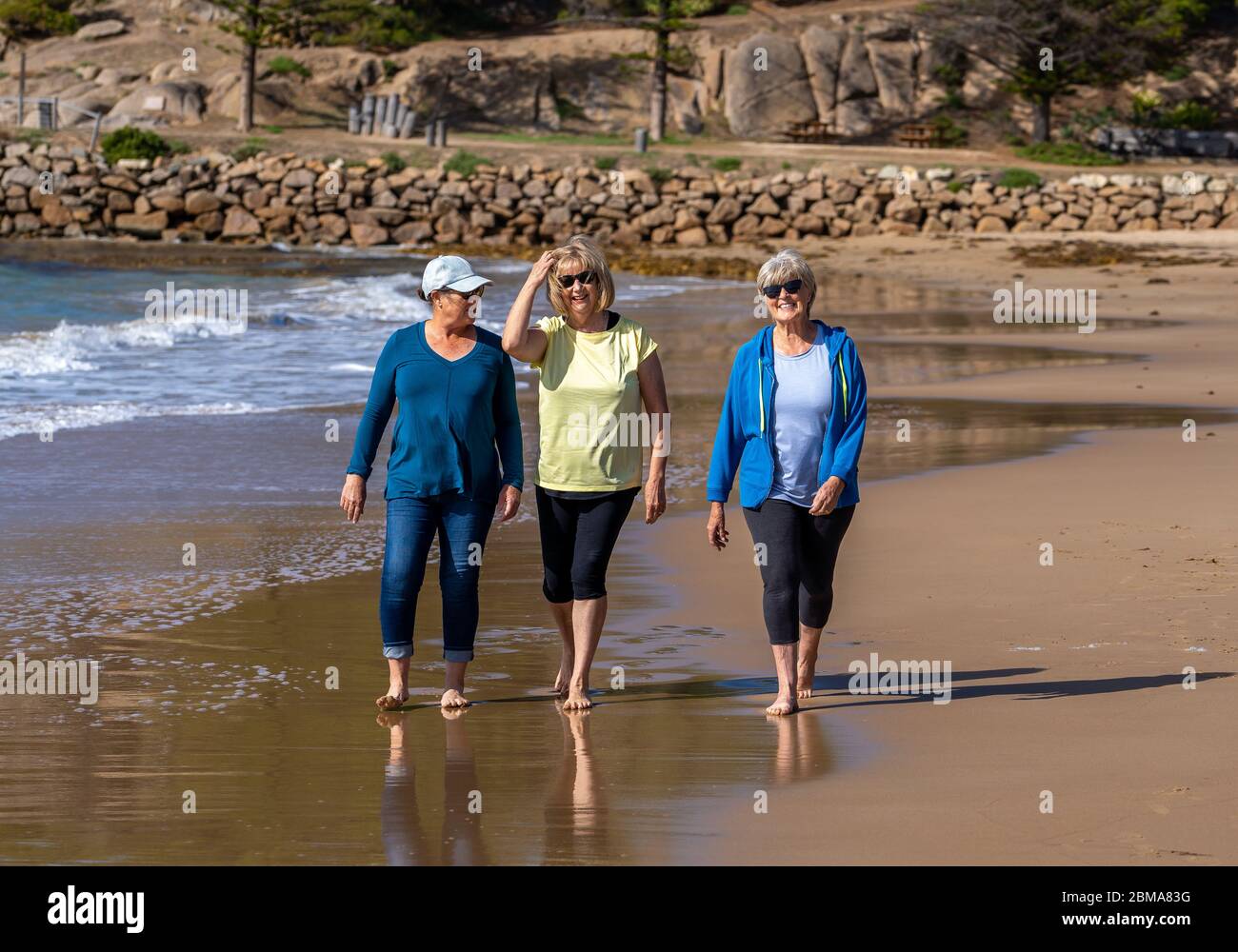 Schöne Gruppe von drei aktiven älteren Frau auf ihren 60ern zu Fuß, Sport und Spaß am Strand. Reife Frauen lachen genießen Spaziergang auf Vacat Stockfoto