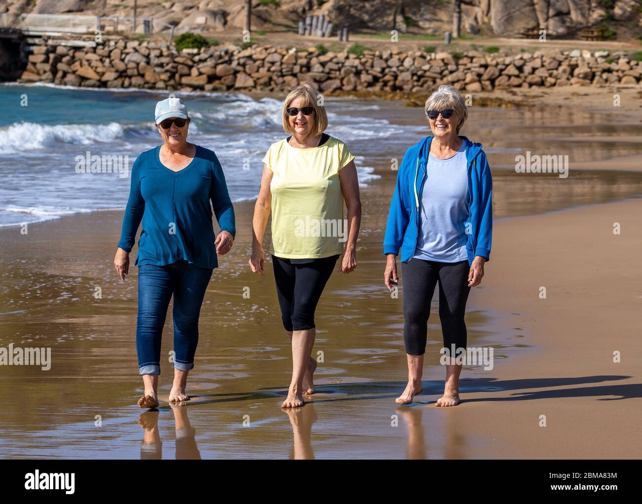 Schöne Gruppe von drei aktiven älteren Frau auf ihren 60ern zu Fuß, Sport und Spaß am Strand. Reife Frauen lachen genießen Spaziergang auf Vacat Stockfoto