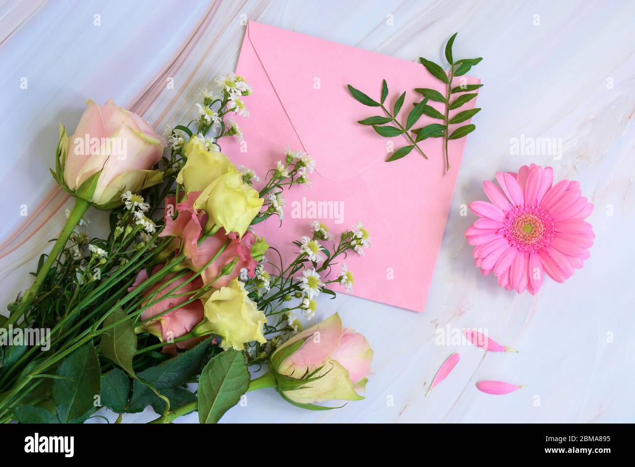Rosa florale Komposition mit Blumen, Umschlag und Blättern auf Marmorgrund. Draufsicht und flacher Lay-Style. Valentinstag, Muttertag, Frauentag Stockfoto