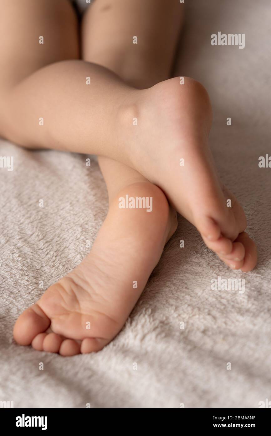 Kindheit, Schlaf, Entspannung, Familie, Lifestyle-Konzept - Füße schlafender Kinder liegen zufällig sorglos gegen ein beige weißes Plaid Stockfoto