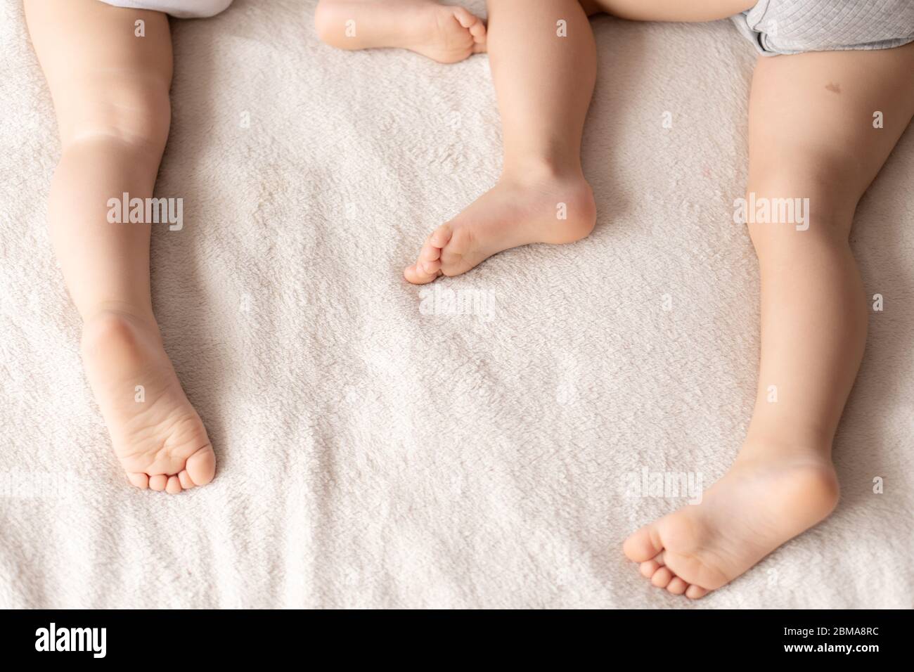 Kindheit, Schlaf, Entspannung, Familie, Lifestyle-Konzept - Füße schlafender Kinder liegen zufällig sorglos gegen ein beige weißes Plaid Stockfoto