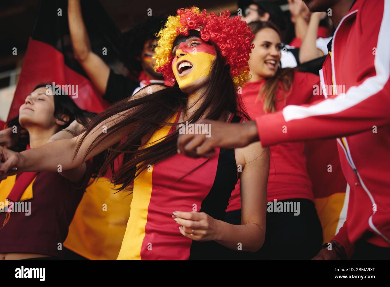 Frau im Stadion trägt eine Perücke und ihr Gesicht in deutschen Flaggen Farben gemalt jubeln für ihre Nationalmannschaft. Weiblich aus Deutschland genießt in Fanzone. Stockfoto