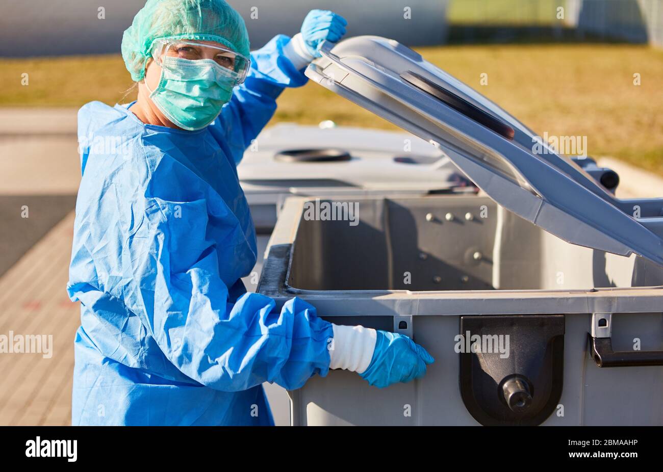 Entsorgung gefährlicher Abfälle in Mülltonne aus der Klinik mit Schutzkleidung wegen Coronavirus-Pandemie Stockfoto