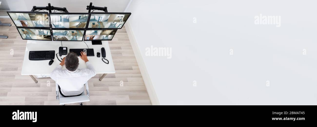 Sicherheitsbediener, der sich CCTV-Kamerabilder auf dem Computer ansieht Stockfoto