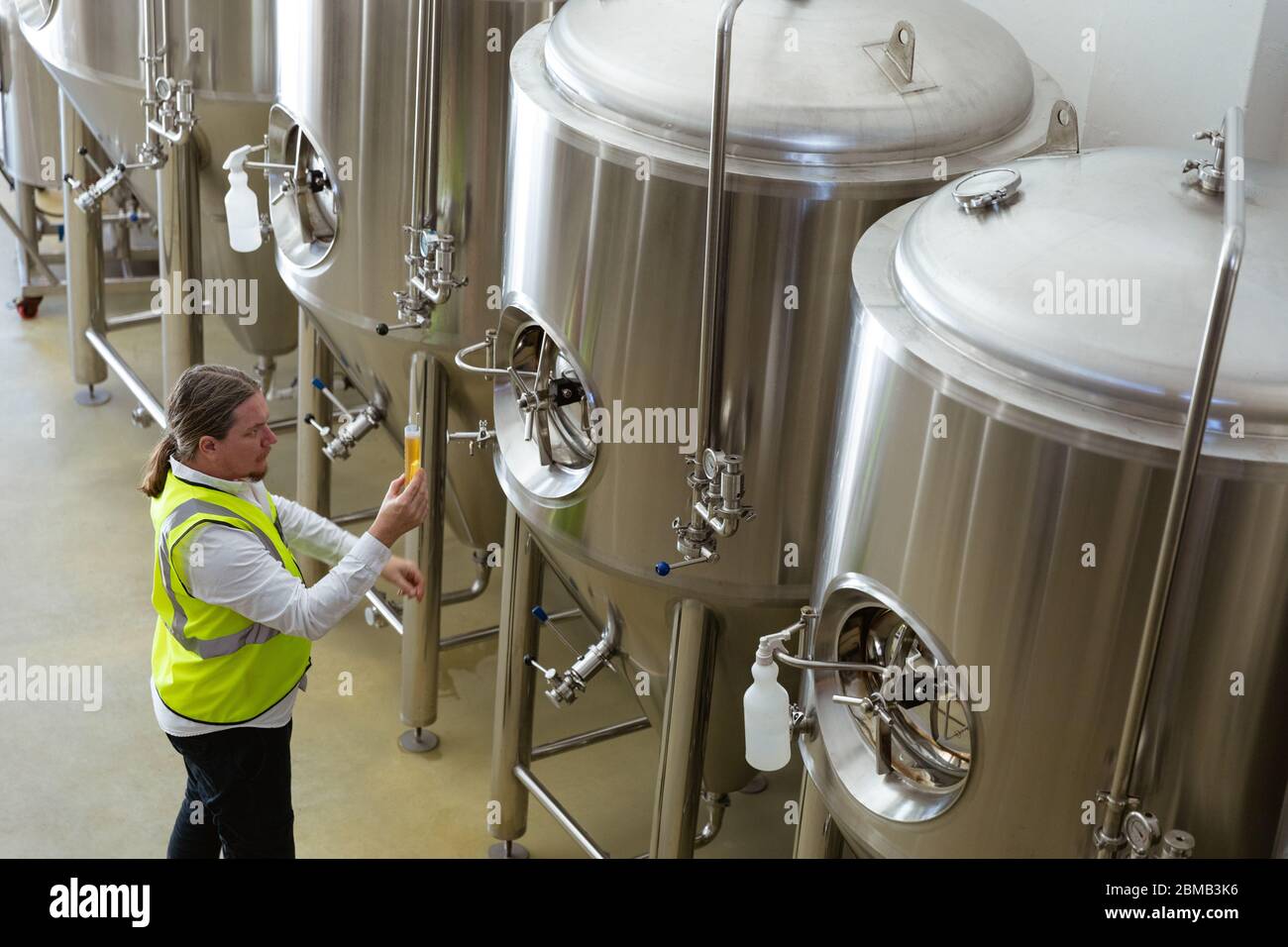 Kaukasischer Mann, der die Farbe des Bieres in einer Brauerei betrachtet Stockfoto