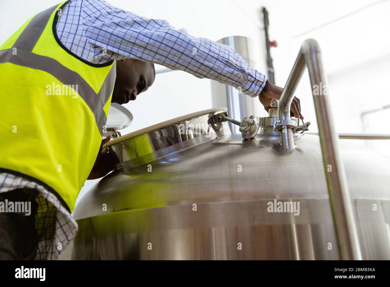 Afroamerikanischer Mann arbeitet und schaut in den Biertank in einer Brauerei Stockfoto