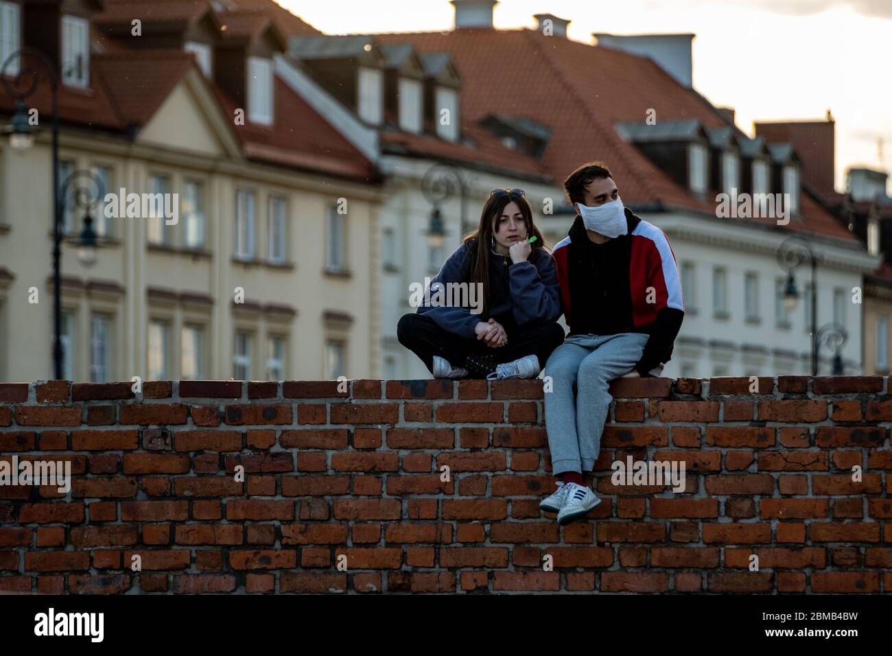 Warschau, Polen. Mai 2020. Am 7. Mai 2020 sitzt ein Paar an einer Wand in Warschau, Polen. Einkaufszentren und Hotels haben in Polen wieder eröffnet, als die Regierung des Landes zusätzliche Beschränkungen aufgehoben hat, die im März zur Eindämmung der Ausbreitung des Coronavirus festgelegt wurden. Kredit: Zhou Nan/Xinhua/Alamy Live News Stockfoto