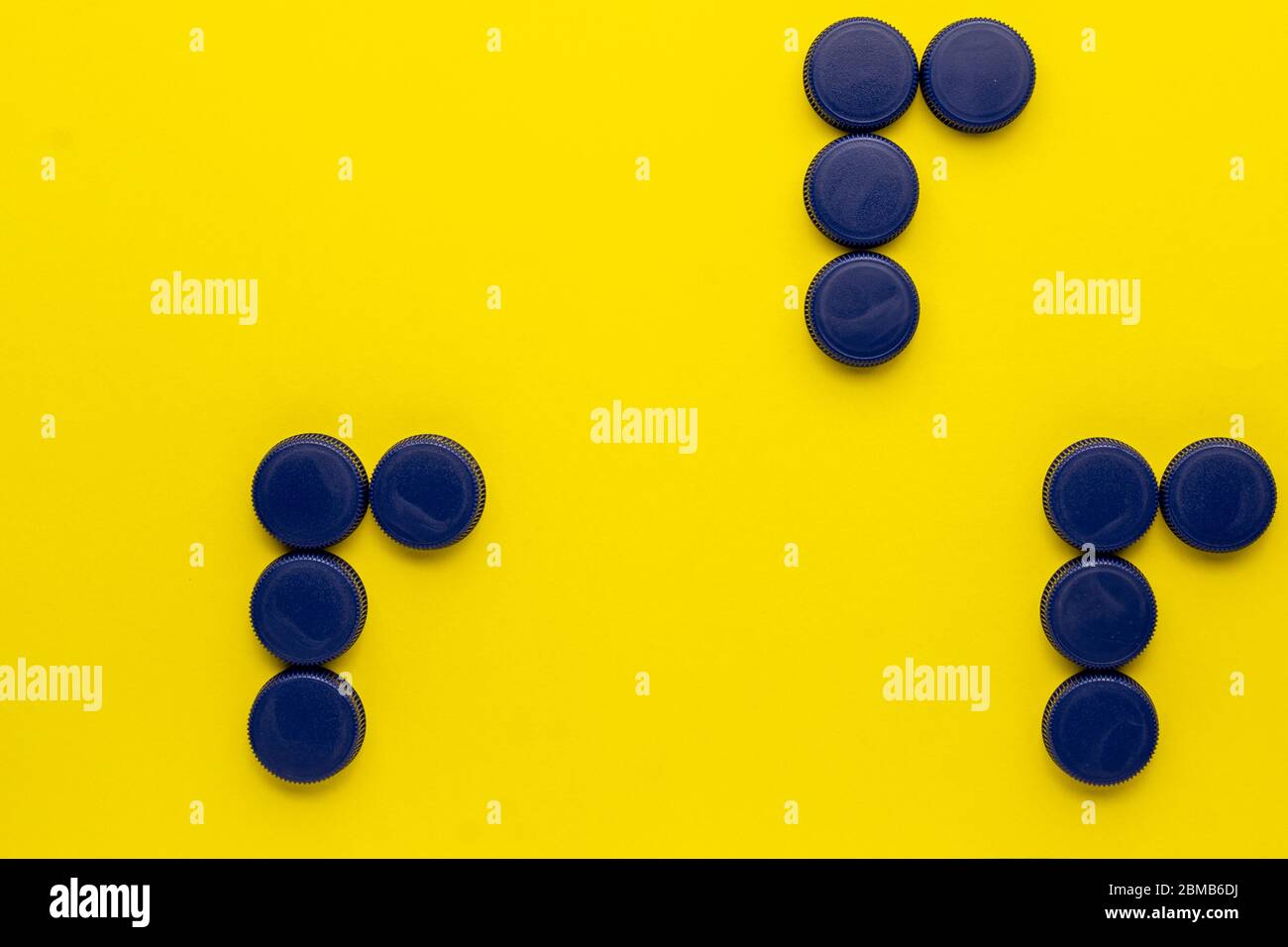 Konzept der drei R's: Recyceln, wiederverwenden, reduzieren. Plastikflaschen-Kappen auf gelbem Hintergrund Stockfoto