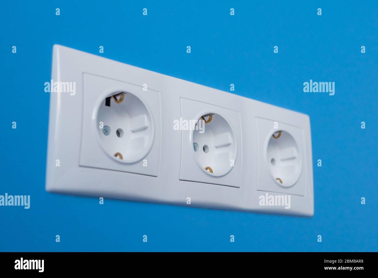 Gruppe von leeren, ungesteckten weißen europäischen Steckdose, Steckdose an der blauen Wand - Nahaufnahme, selektiver Fokus. Ausstattung, Design, Strom Stockfoto