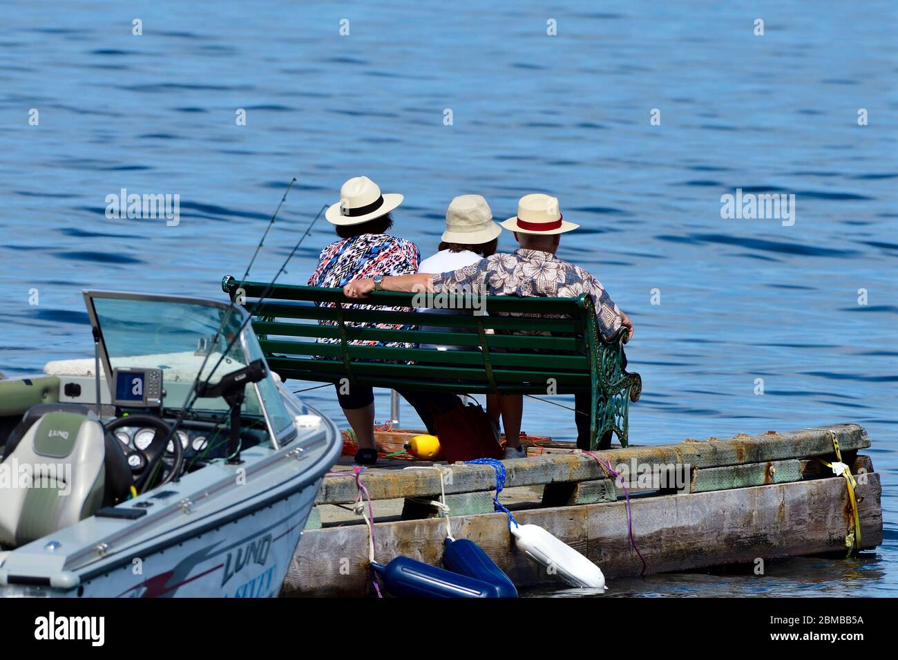 Drei Personen sitzen am Ende eines Bootsanlegesteg und ruhen sich von den Tagesaktivitäten auf Vancouver Island, British Columbia, Kanada aus. Stockfoto