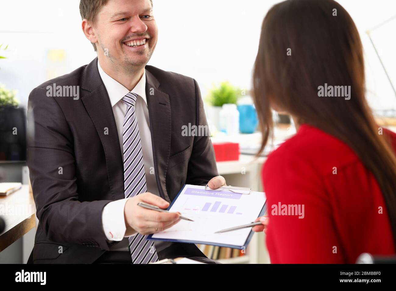 Der Mann im Anzug hält der Frau ein Unterschriftdokument vor Stockfoto