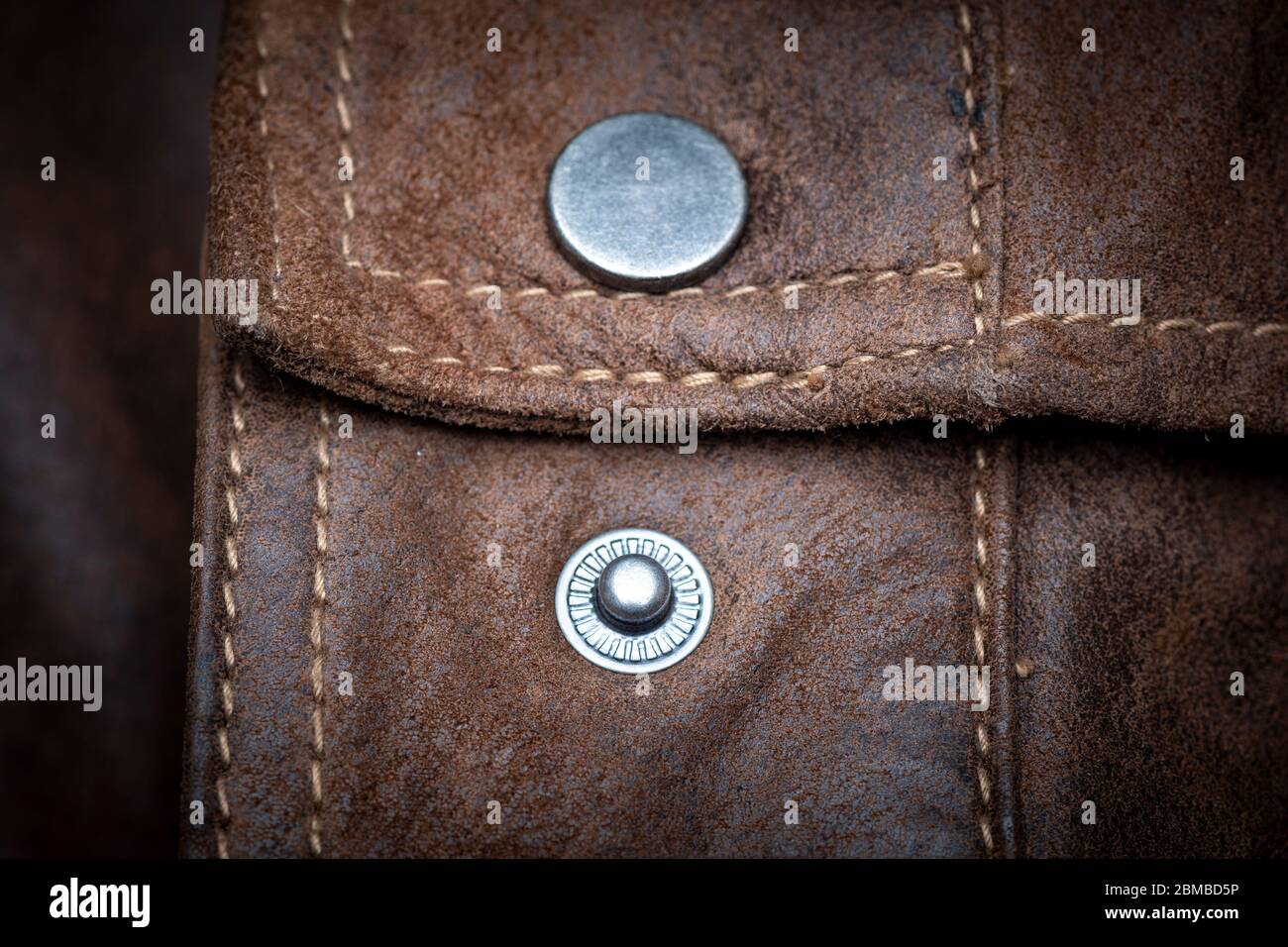 Druckknopfverschluss aus Metall an einer braunen Lederjacke, Nahaufnahme. Stockfoto