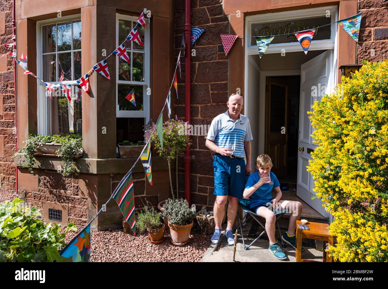 North Berwick, East Lothian, Schottland, Großbritannien. Mai 2020. VE Day Feiern: Chris Paterson und sein Sohn Rory heben ein Glas Limonade zum 75. Gedenken an den Sieg in Europa Tag um 15 Uhr während der Covid-19 Coronavirus Pandemie gesperrt Stockfoto