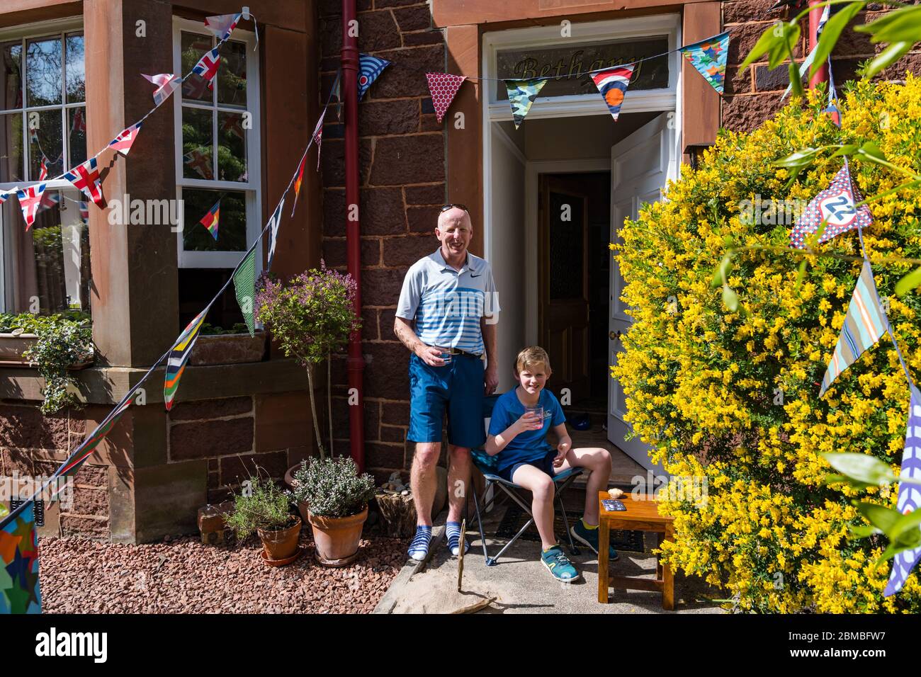 North Berwick, East Lothian, Schottland, Großbritannien. Mai 2020. VE Day Feiern: Chris Paterson und sein Sohn Rory heben ein Glas Limonade zum 75. Gedenken an den Sieg in Europa Tag um 15 Uhr während der Covid-19 Coronavirus Pandemie gesperrt Stockfoto