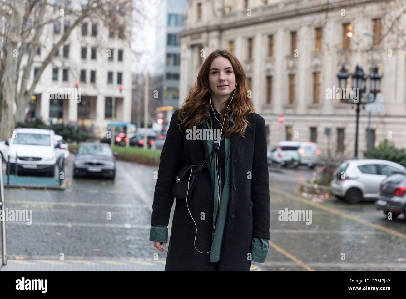 Junge Frau trägt schwarzen Mantel posiert in der Stadt Stockfoto