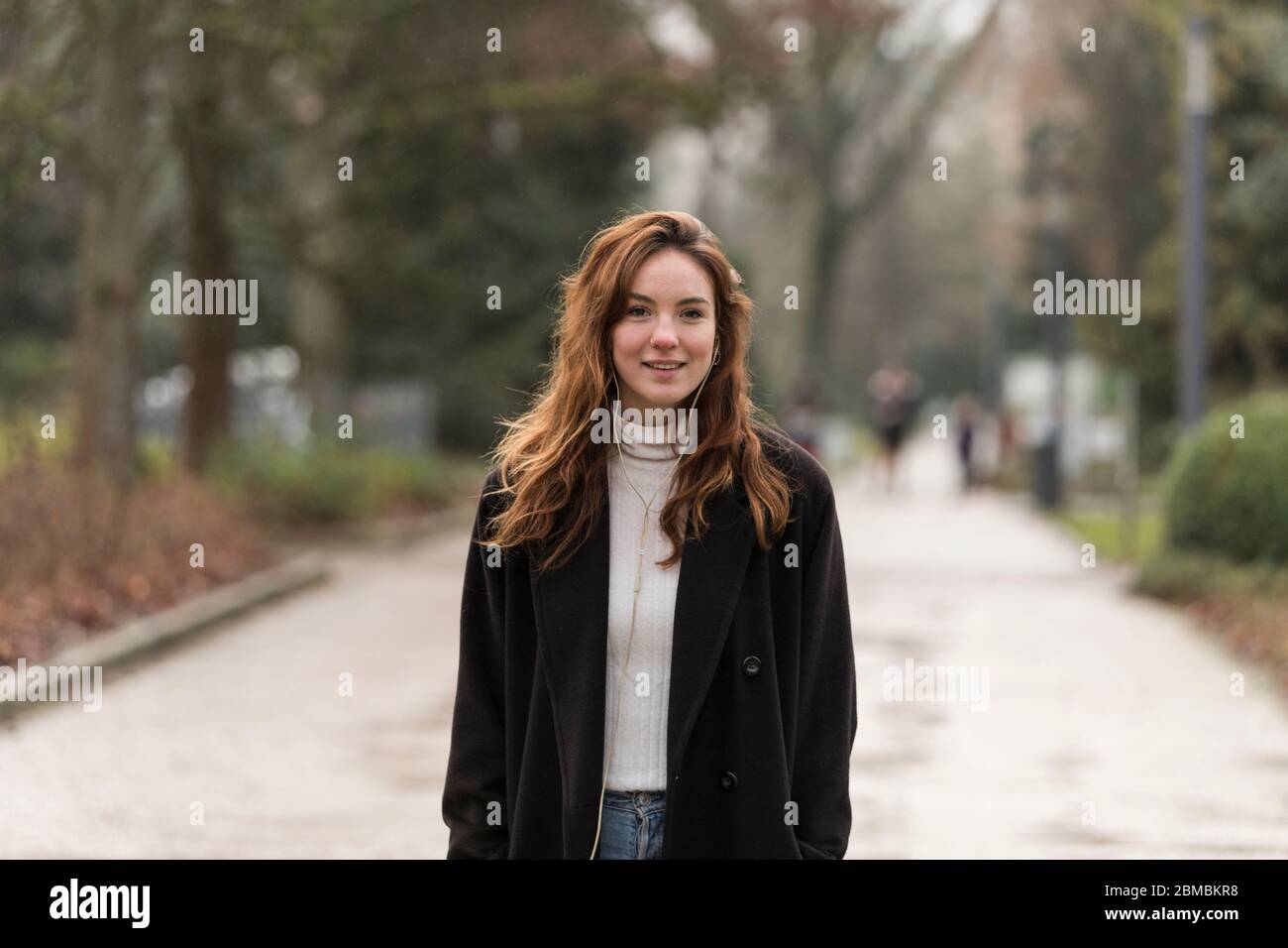 Schöne junge Frau mit Kastanie Brown Haar lächelnd in Park Stockfoto