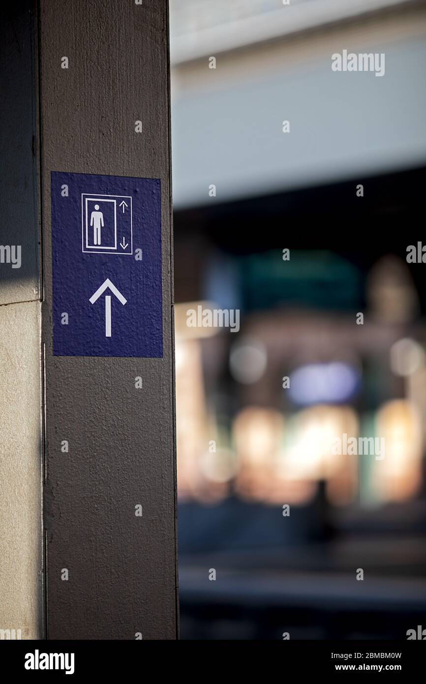 Symbol mit einer menschlichen Figur und Pfeilen, die den Weg zum nächsten Aufzug zeigen Stockfoto