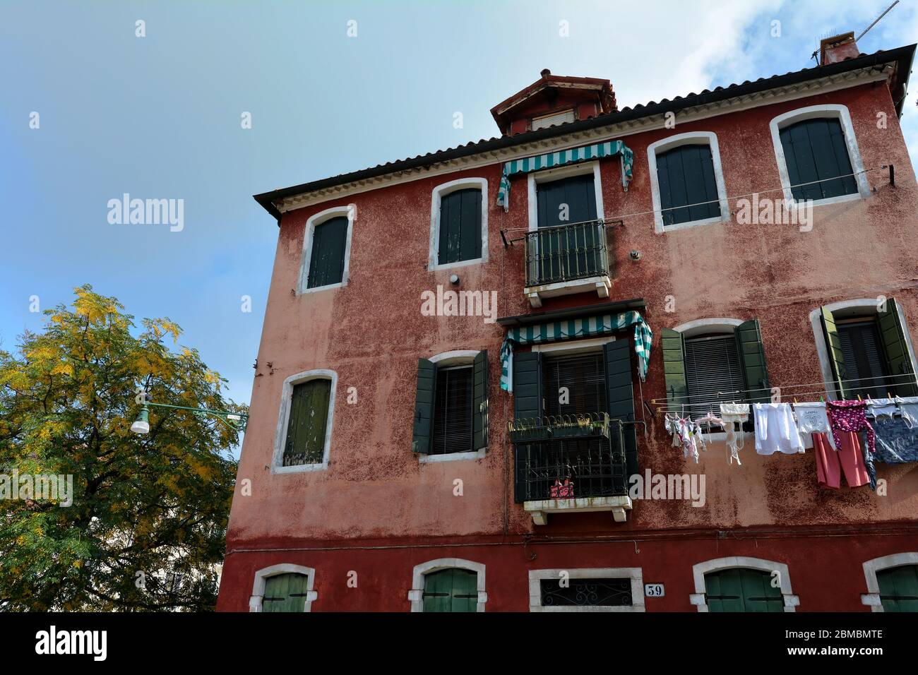 Wäsche trocknet aus, hängt an einer Wäscheleine zwischen zwei Gebäuden in Murano, Italien Stockfoto