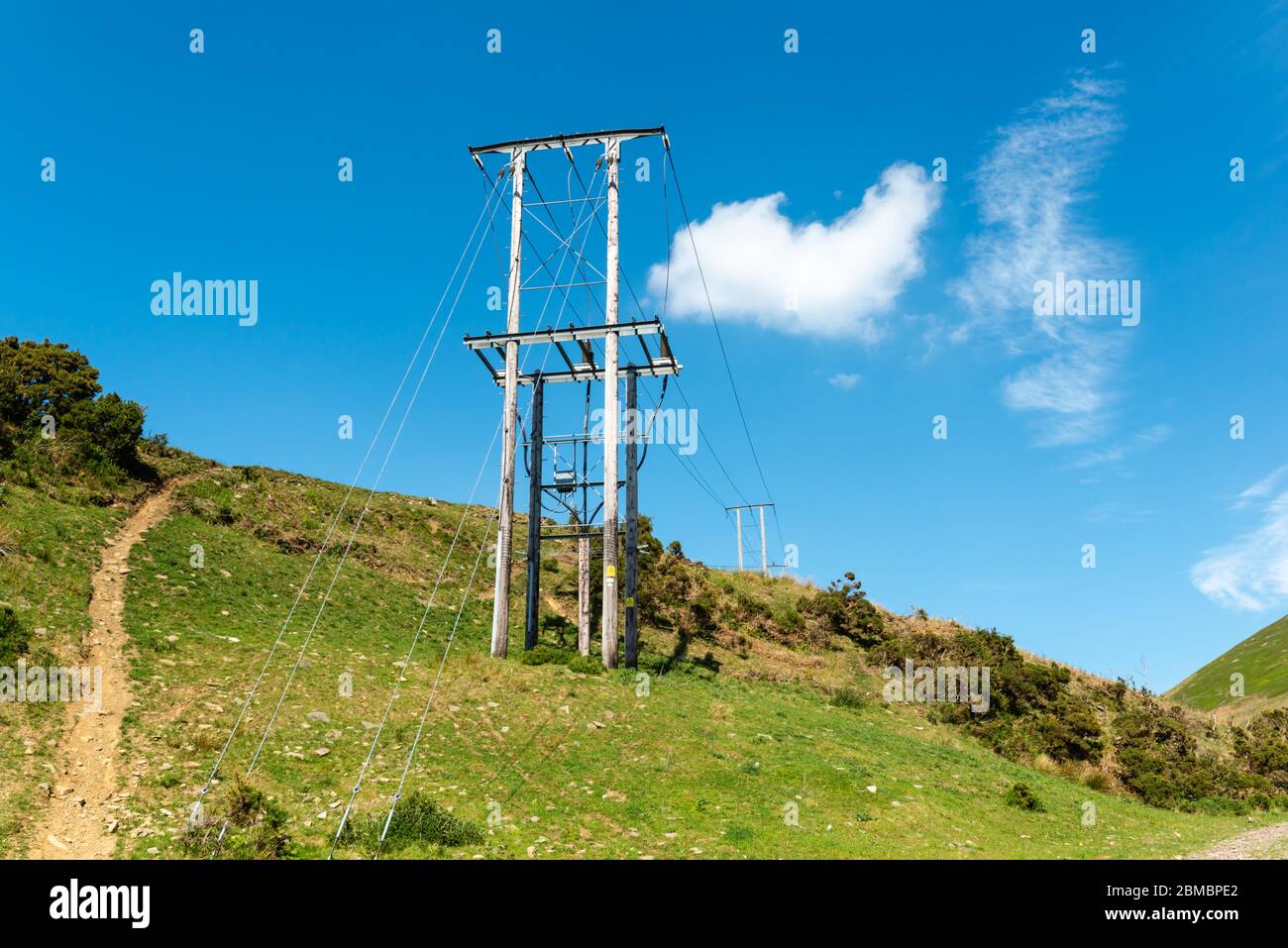 Powerlines auf einem Hügel mit einem Schlammweg daneben Stockfoto
