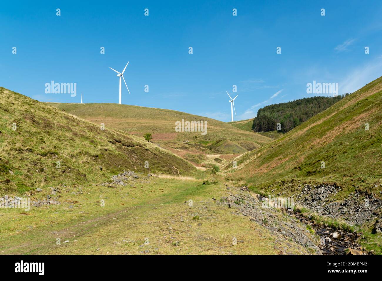 Talbach mit Windturbinen und Wald auf entfernten Hügel Stockfoto