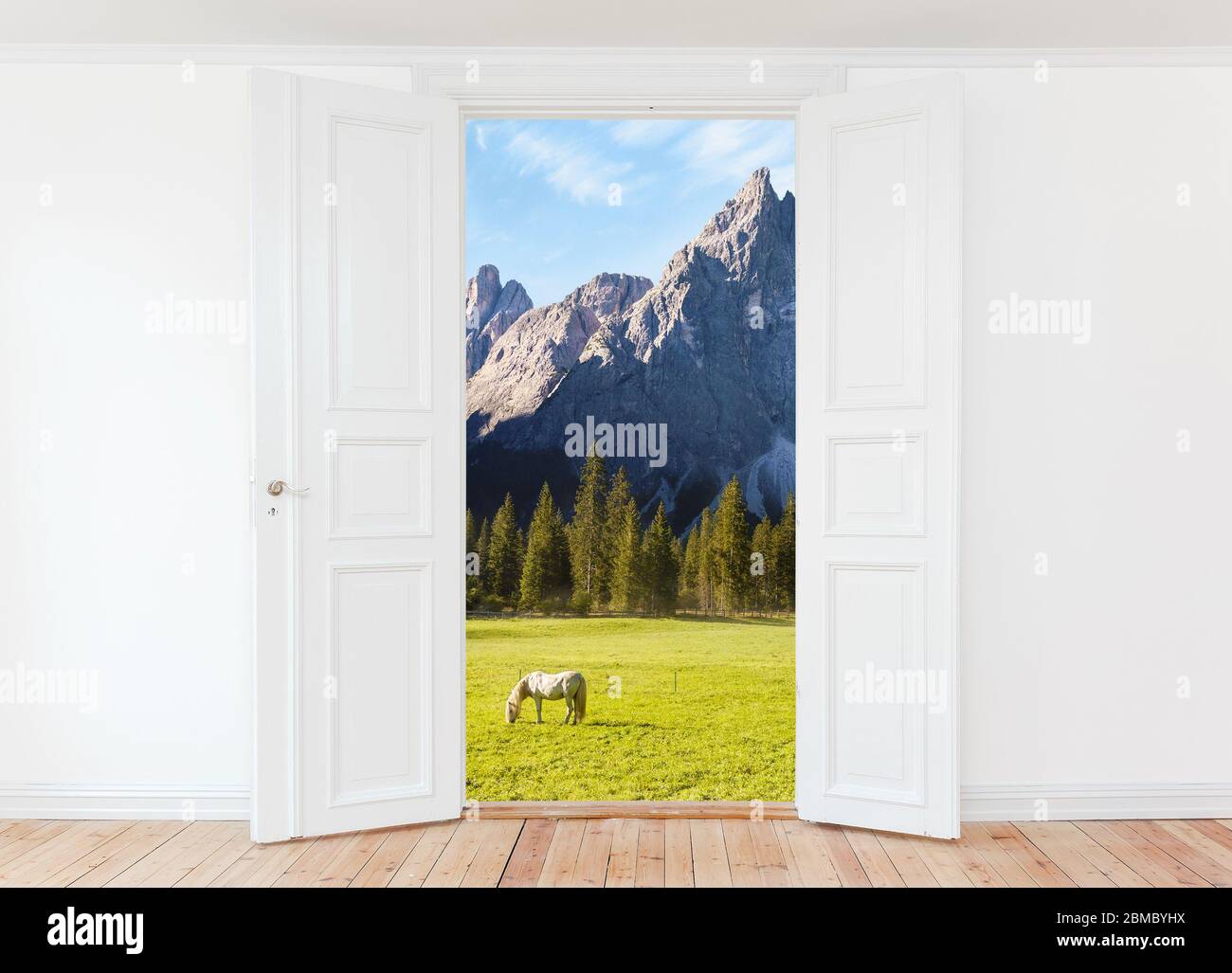 Weit geöffnete Tür in leerem Raum mit Blick auf die Berglandschaft und grasenden Pferd im Freien Stockfoto