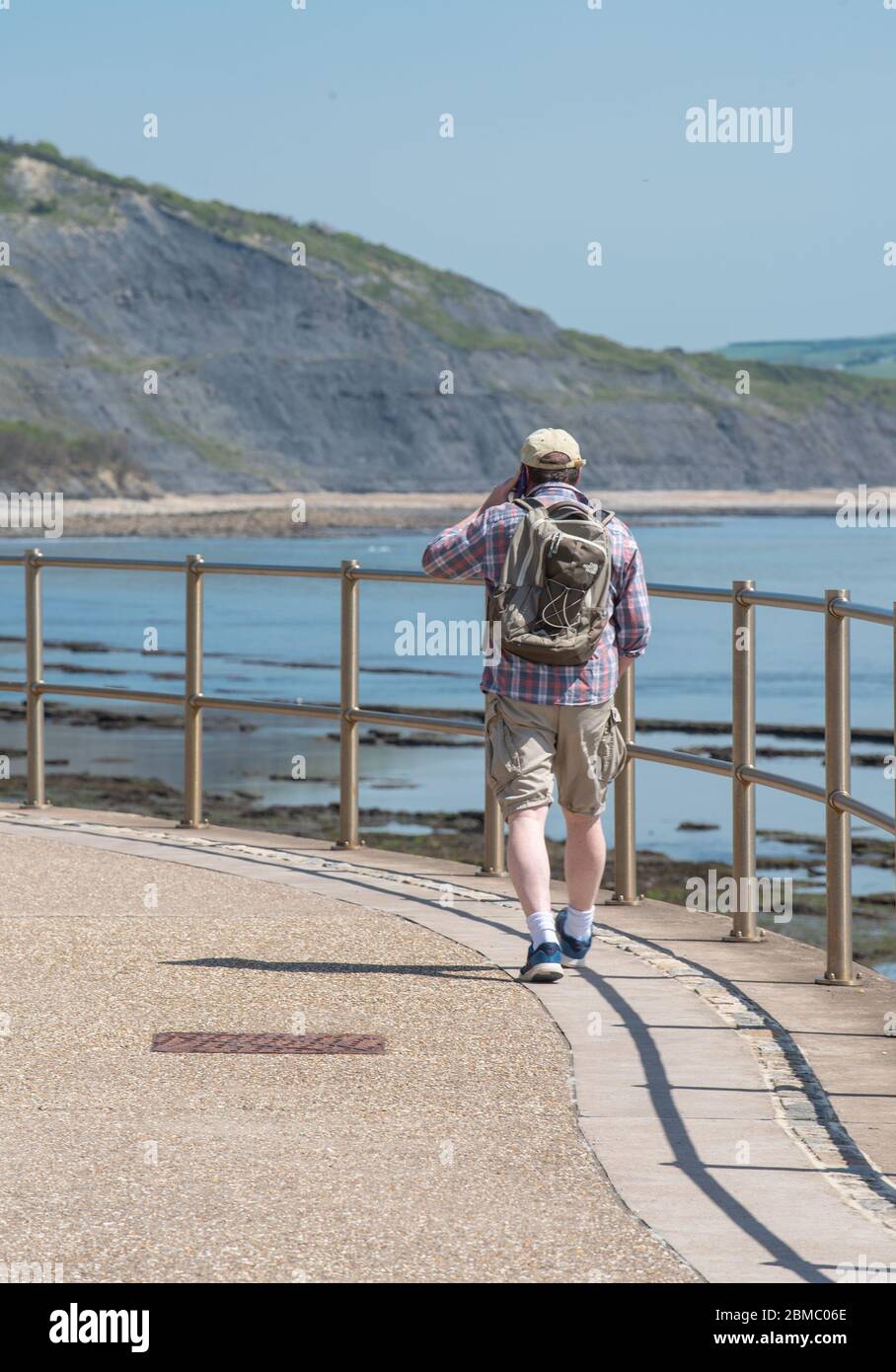 Lyme Regis Dorset, Großbritannien. Mai 2020. UK Wetter: Ein heißer und sonniger Feiertagnachmittag bei Lyme Regis, West Dorset. Ein Mann geht am Meer entlang in Richtung Charmouth. Kredit: Celia McMahon/Alamy Live News Stockfoto