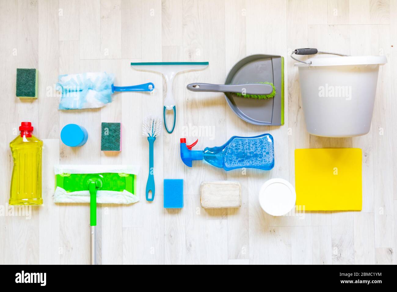 Flaches Lay mit Sammlung von Reinigungsmaterialien auf einem hellen Holzhintergrund Stockfoto