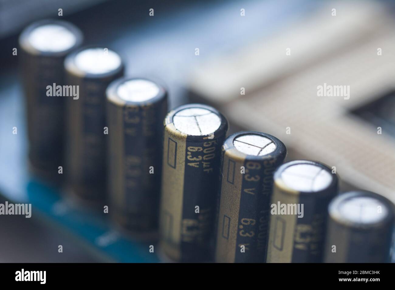 Fragment der Hauptplatine mit Elektrolytkondensatoren. Kapazitive Baugruppe. Kondensator für elektronische Bauteile auf der blauen Leiterplatte Stockfoto