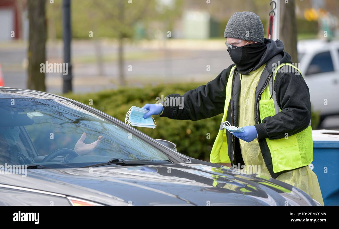 Schaumburg, Illinois, USA. Mai 2020. Austin MEYER, Mitarbeiter des Dorfes Schaumburg, verteilt bei einer kostenlosen Maskenverteilung am Freitag, 8. Mai 2020, kostenlose Masken an Bewohner des Vororts Chicago, Illinois. Das Dorf plante, während der dreitägigen Veranstaltung rund 70,000 Masken auszuhändigen. Ab dem 1. Mai müssen alle Personen in Illinois über 2 Jahre eine Maske oder Gesichtsbedeckung tragen, während sie in der Öffentlichkeit oder während der Arbeit sind, wenn 6 Fuß soziale Distanzierung unmöglich oder unpraktisch ist. Das Vorstadtdorf hat eine Bevölkerung von rund 158,000. Quelle: ZUMA Press, Inc./Alamy Live News Stockfoto