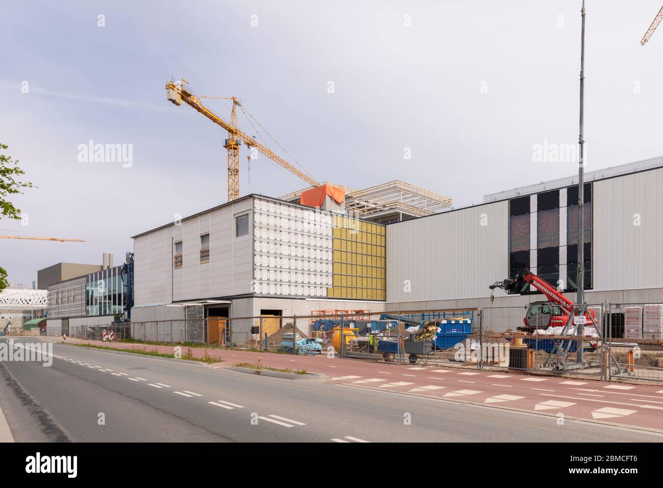 Veldhoven, Niederlande, 8. Mai 2020. Eine Baustelle der neuen ASML-Gebäude mit einem großen gelben Kran und Baumaterialien auf einem sonnigen Stockfoto