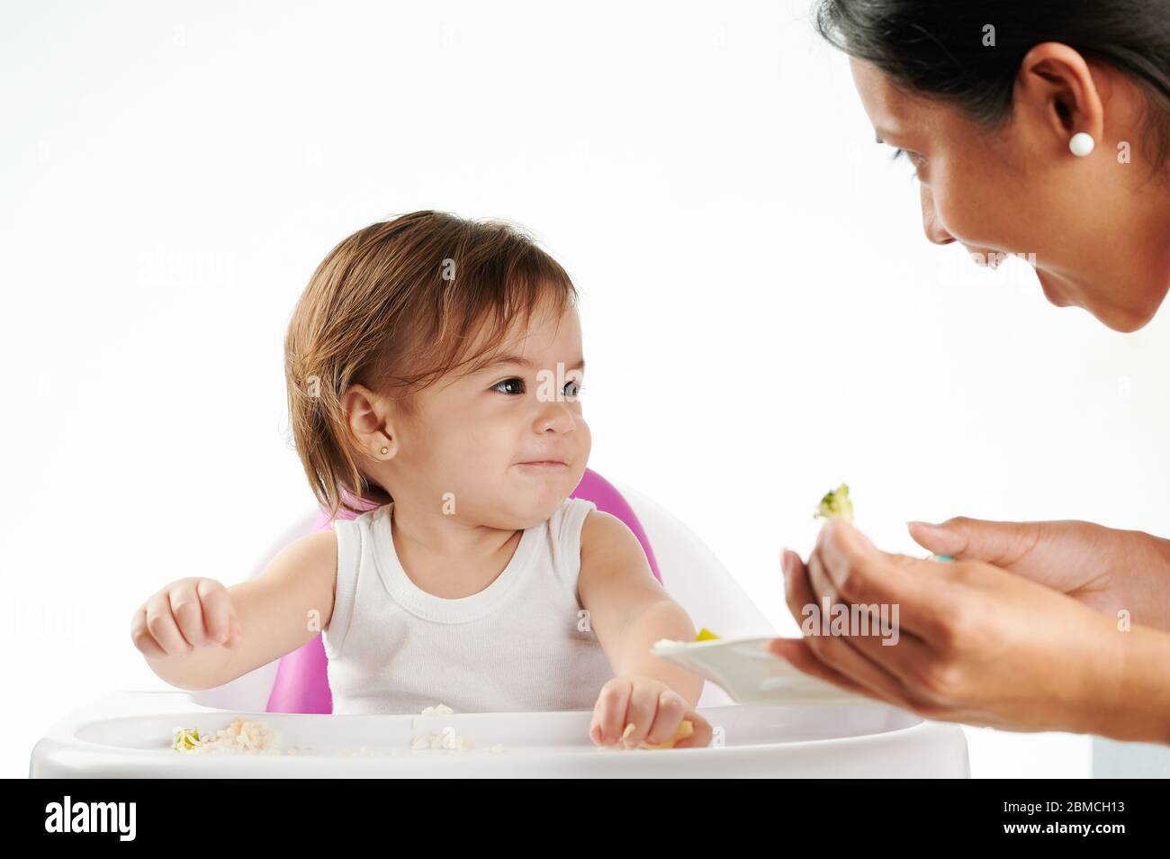 Mama füttern Baby Mädchen mit gesunder Nahrung isoliert Stockfoto