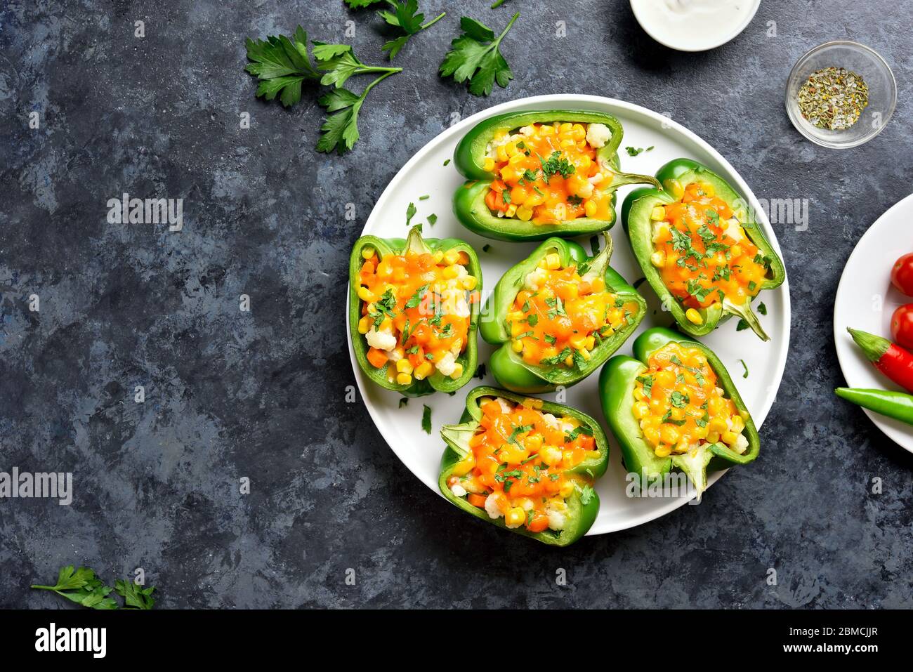 Gebackene grüne Paprika mit Mais, Karotten, Blumenkohl auf weißen Platte über der blauen Stein Hintergrund mit freie Platz gefüllt. Gesunde Diät- oder vegetarische f Stockfoto