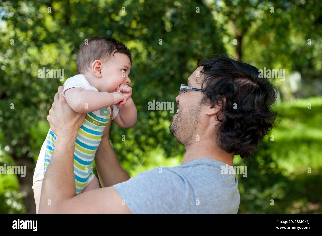 Glücklicher junger Vater hält sein Baby im Park. Vatertag Konzept´s. Großer Kopierplatz Stockfoto