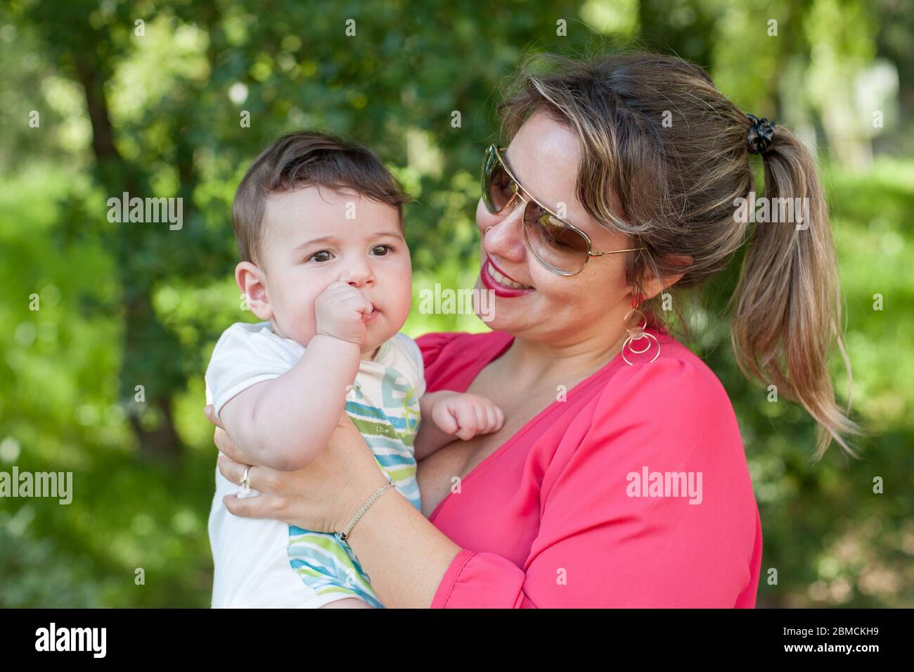 Glückliche Mutter hält ihr Baby Junge in ihren Armen im Park. Stockfoto