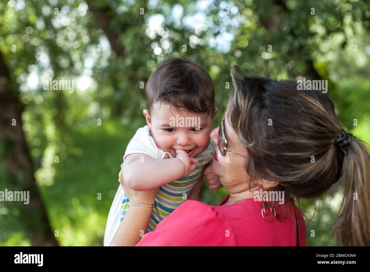Glückliche Mutter hält ihr Baby Junge in ihren Armen im Park. Großer Kopierplatz. Stockfoto