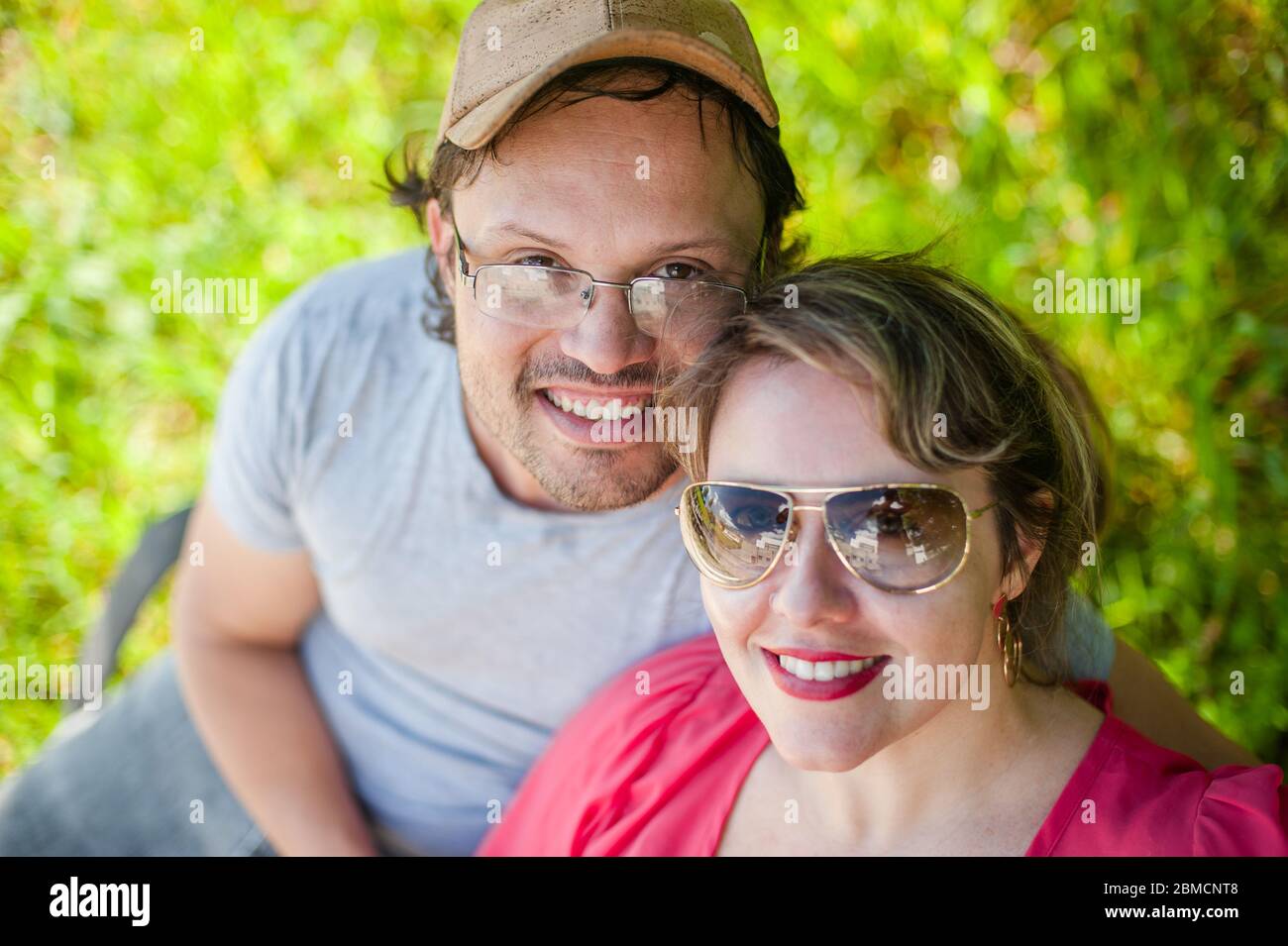 Hochwinkelansicht eines Paares, das die Kamera in einem grünen Hintergrund betrachtet. Stockfoto