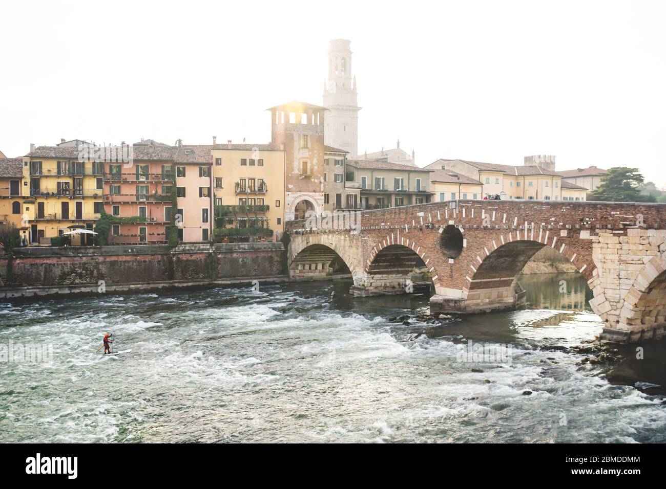 Flusssurfer bei Sonnenuntergang mit Blick auf die Stadt mit Hintergrundbeleuchtung bei Ponte Pietra in Verona, Italien Stockfoto