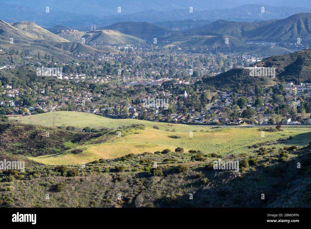 Grasbewachsene Wiesen in Santa Monica Mountains National Recreation Area und Newbury Park Häuser und Straßen. In Ventura County, Kalifornien. Stockfoto