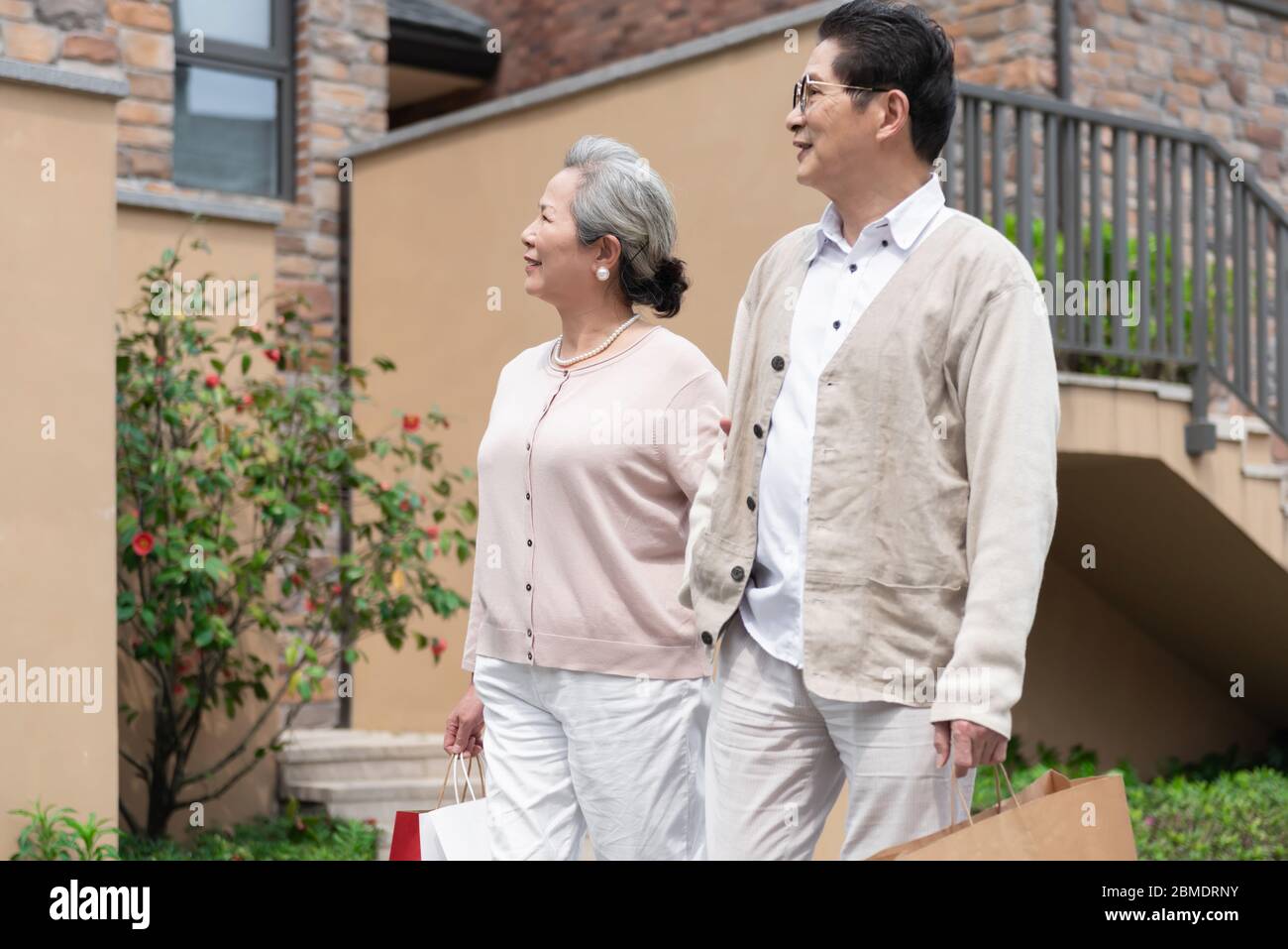 Ein älteres asiatisches Paar, das Einkaufstaschen in der Gemeinde hält Stockfoto