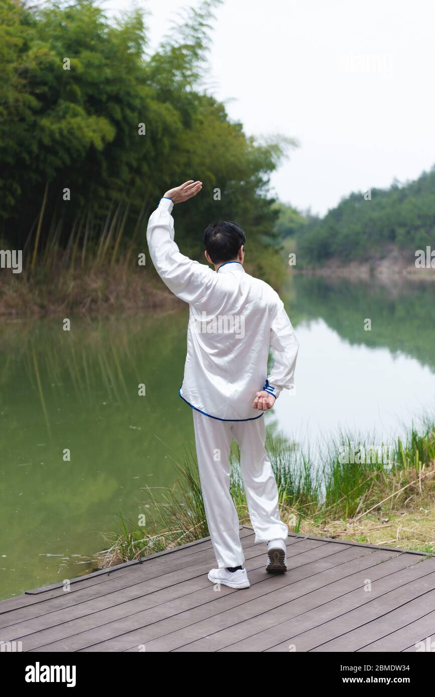 Ein älterer asiatischer Mann, der am See Sport macht Stockfoto