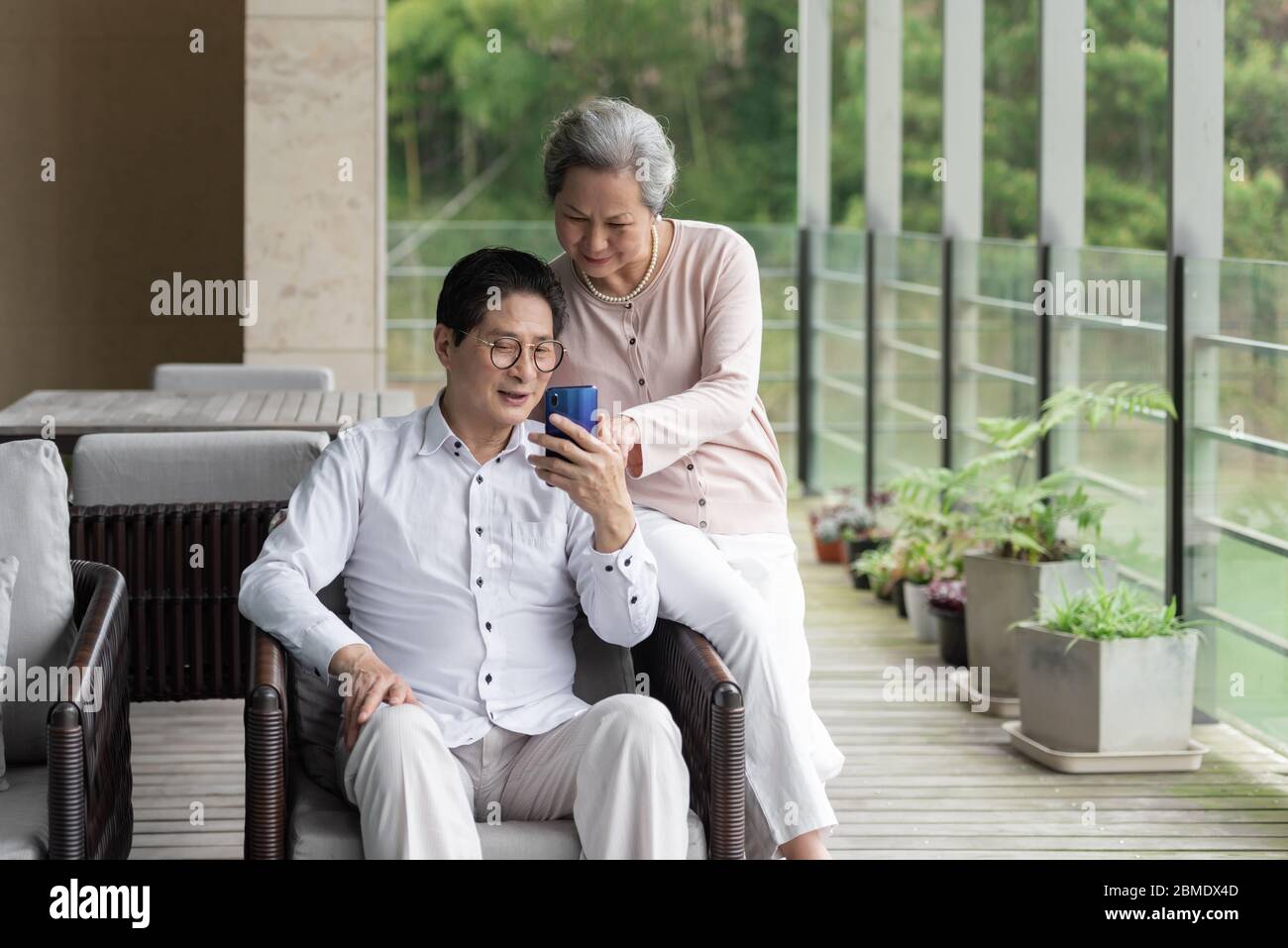 Ein asiatisches älteres Paar auf einem Outdoor-Stuhl Stockfoto