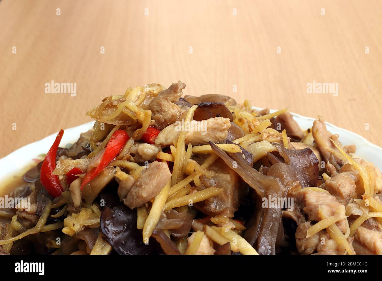 Hähnchenbrust mit Ingwer aus Pilzen, Knoblauch, frischen Paprika auf einem Teller und auf einem Holzhintergrund gelegt. Stockfoto