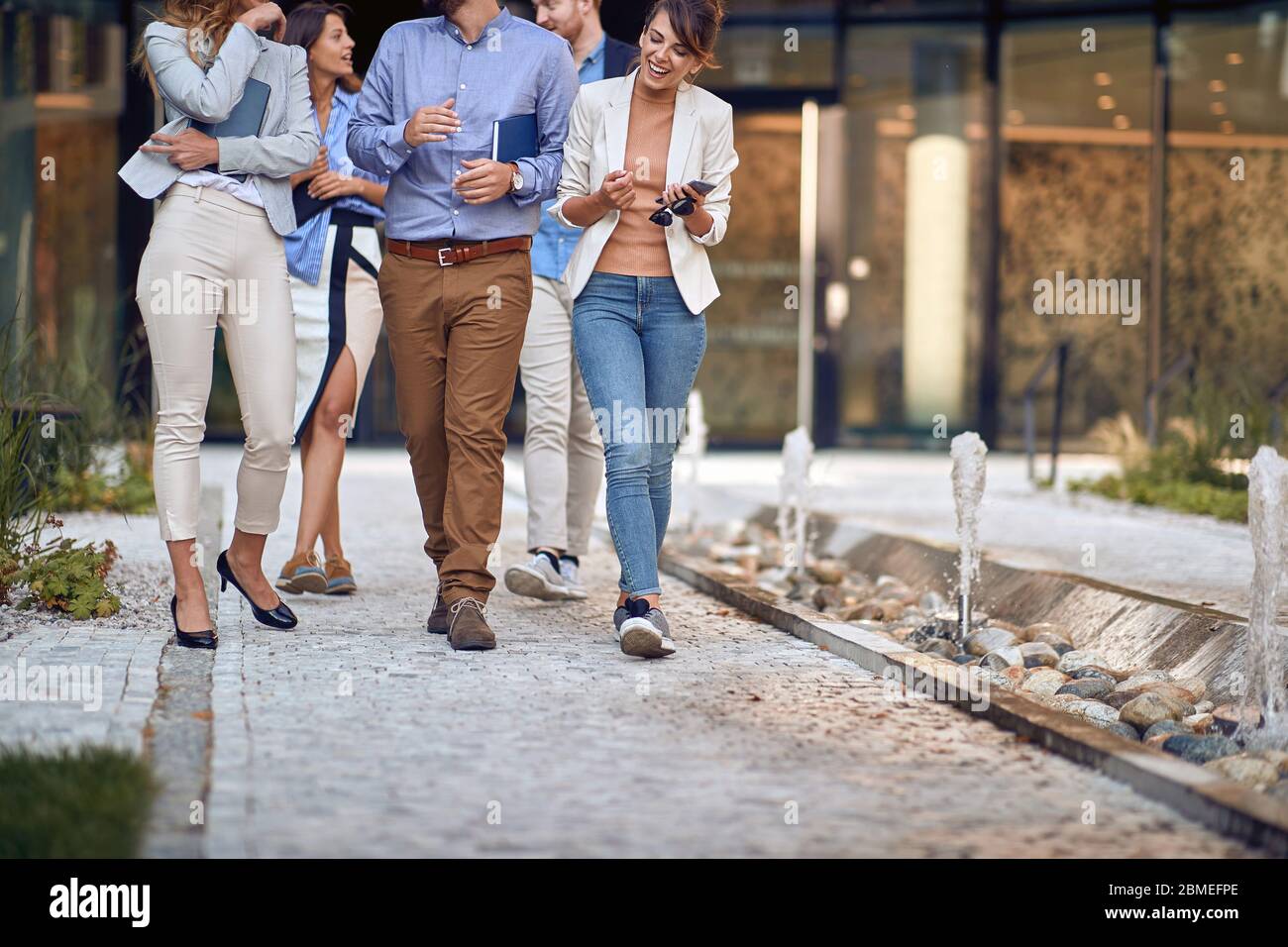 Moderne lächelnde Geschäftsleute gehen zu Kaffeepause. Stockfoto