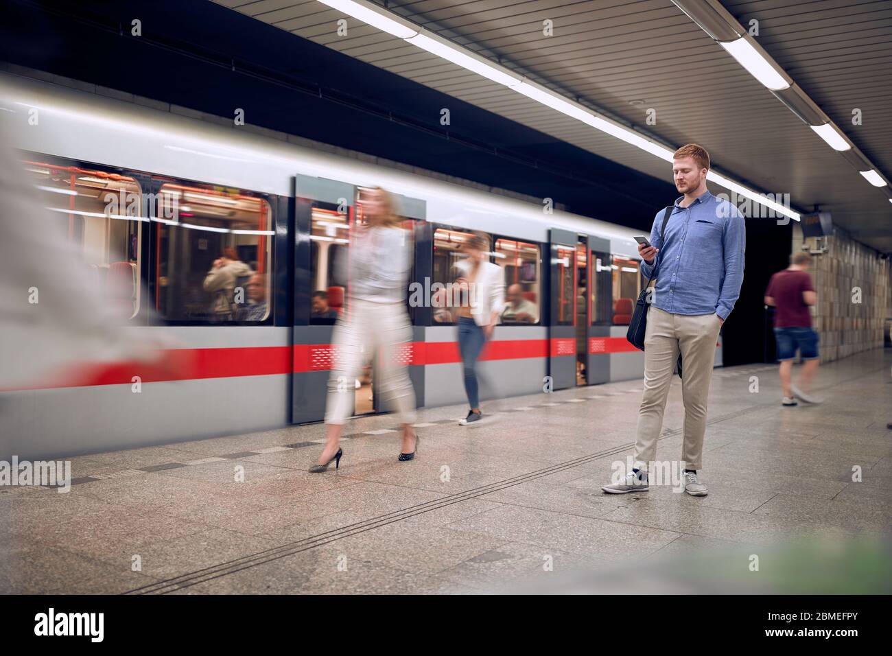 Business junger Mann wartet auf U-Bahn und SMS-Nachricht. Stockfoto