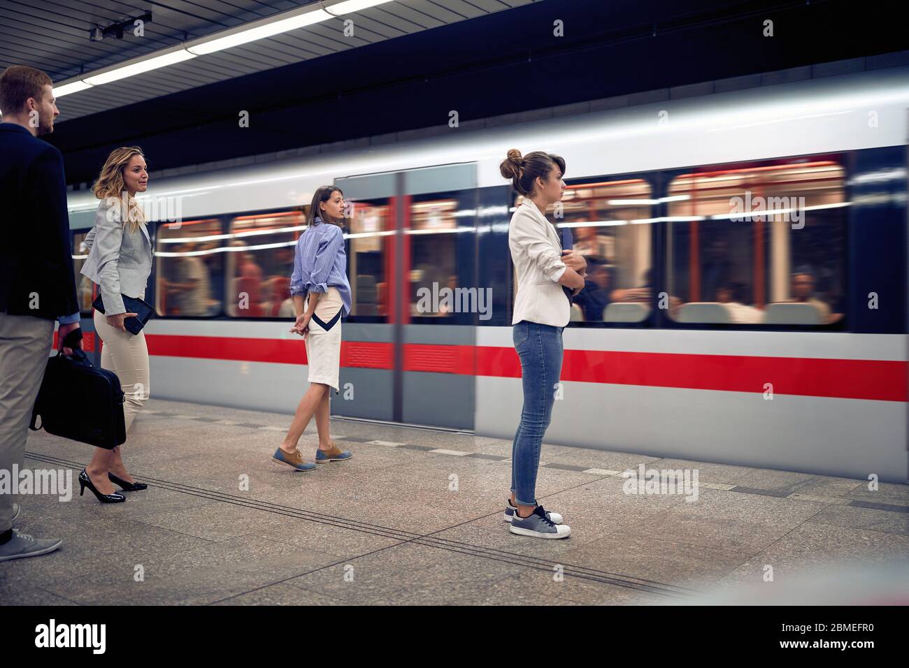 Geschäftsleute warten auf die U-Bahn in der U-Bahn.Junge Menschen warten auf einen Zug in der U-Bahn. Stockfoto